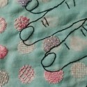 a detail view of pink and white texture stitches and beading inside circles on a sea-green cloth