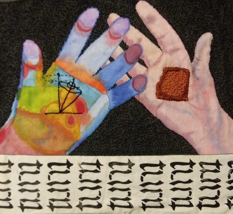 a multicolored left hand and pink right hand have open palms overlapped on a black background with seed stitches. A piece of textured red clay tile sits on the right hand. A black outline of a diagram of a spinning top is on the left hand, a row of repeating words saying turn borders the bottom edge